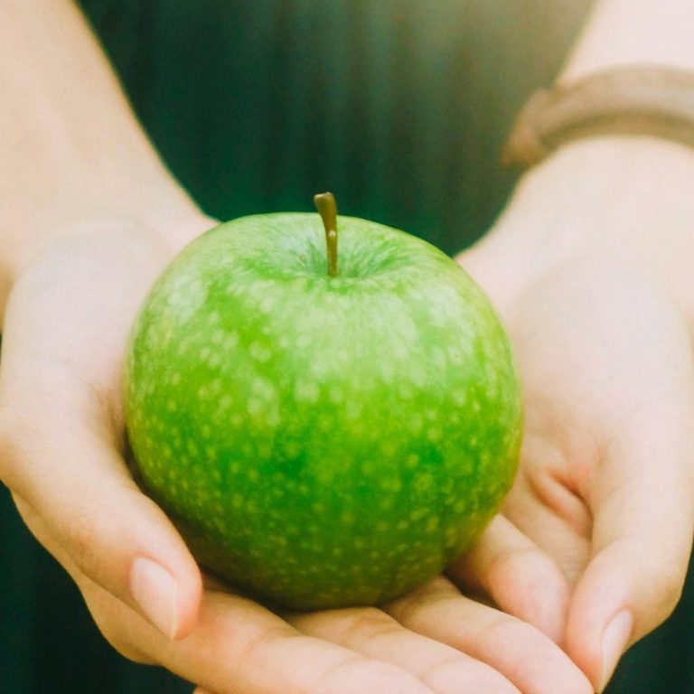 grüner Apfel liegt in zwei Händen