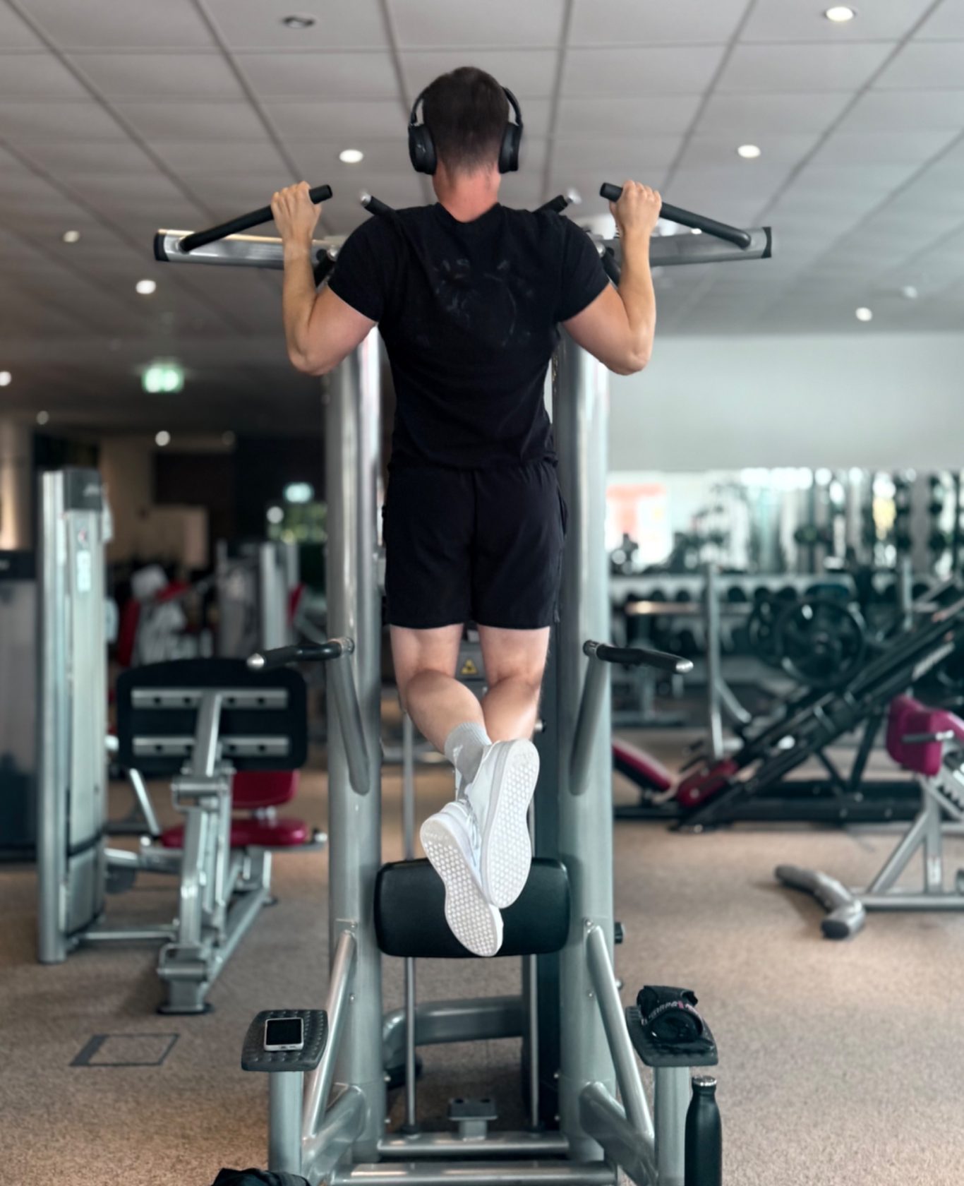 Mann macht Klimmzüge an einem Fitnessgeräte in einem modernen Fitnessstudio.